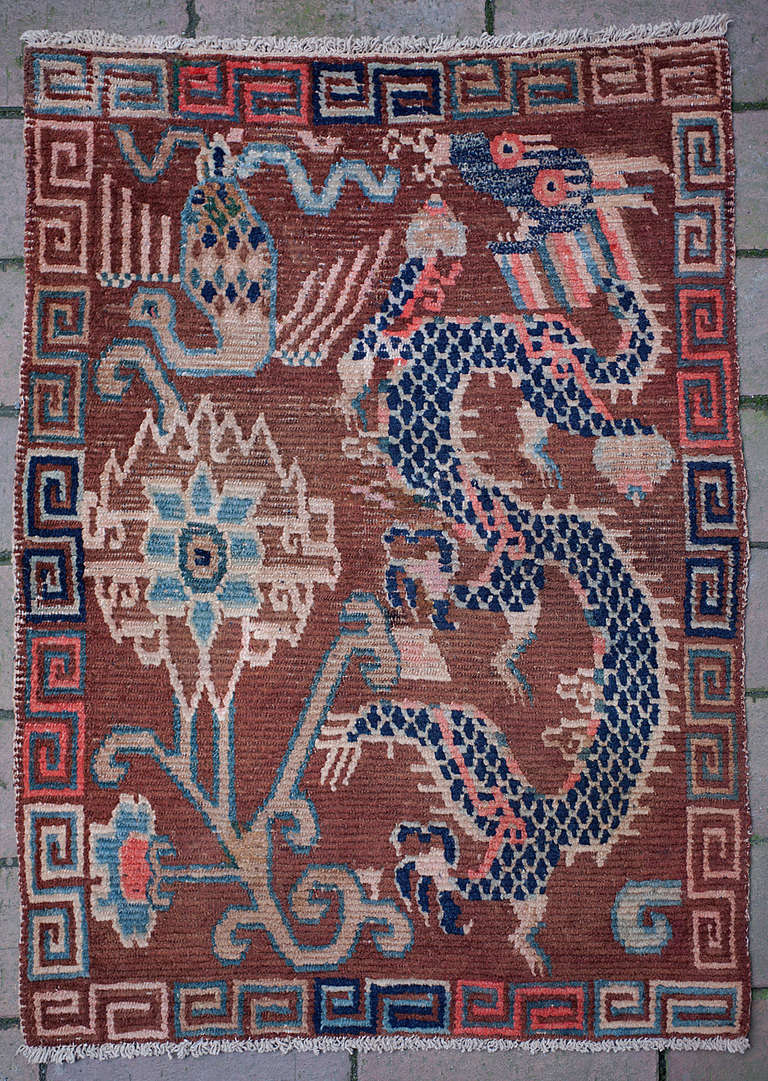 This delightful Tibetan sitting rug (Khagangma) shows a unique and early take on the classic dragon and phoenix design. 
The warm brown background sets the stage for an all-natural dyes design with dragon and phoenix. The subtle colouring