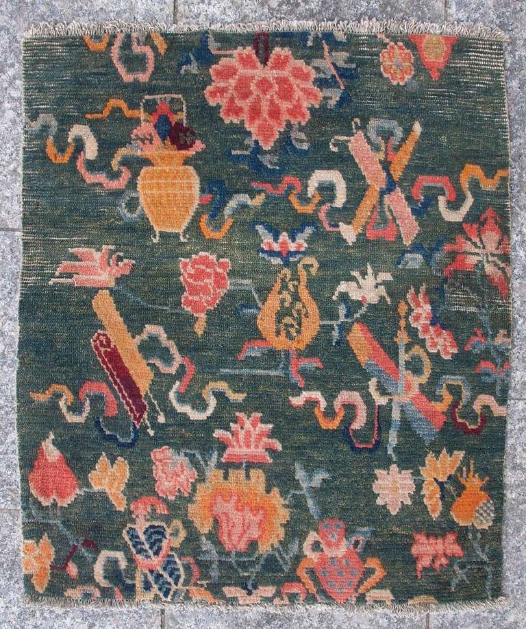 
This lovely Tibetan sitting rug has a beautiful green background decorated with floral elements and Buddhist symbols. 

The vivid green is reminiscent of a lush meadow with a variety of flowers in full bloom-peonies, lotus, orchids, etc with