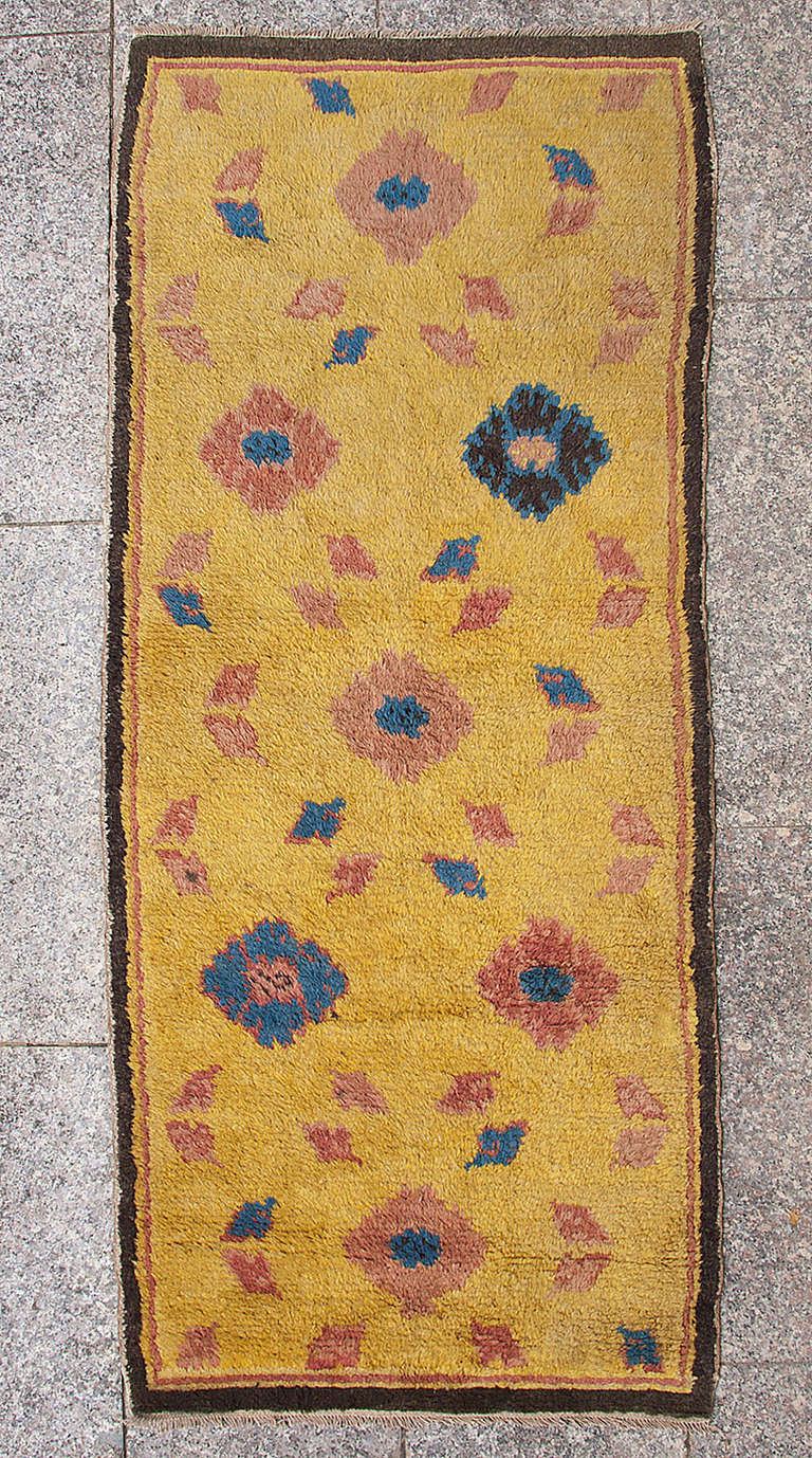 This antique rug was made in North-western China to cover the long rows of monks benches in temples and monasteries.
The vibrant yellow field is characteristic of the rugs made in Ningxia since at least the 15th century. Peonies in four colour