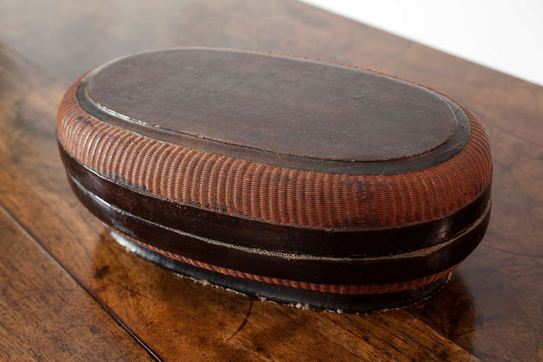 This simple and charming Chinese oval box with lid, made from black lacquer and basket weave, dates back to the Ming dynasty (1368-1644). 

This piece from Shanxi province is made using a traditional lacquer technique dating back to the Song
