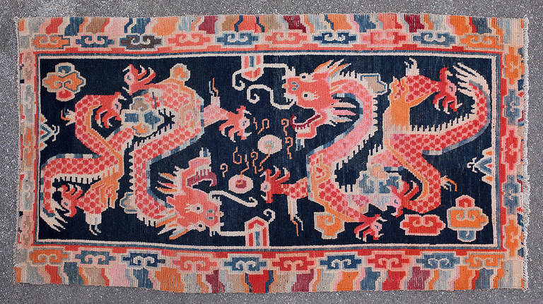 This lovely blue ground double dragon Khaden is a true classic. 

Two energetic red dragons are set against an indigo blue background and fly amongst the clouds over Mount Meru playing with flaming pearls. The powerful dragons have expressive