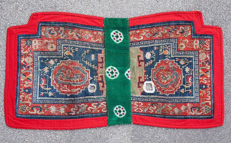 Lovely Tibetan saddle rug with dragon medallions and natural dyes.

This Tibetan saddle rug still has the typical hand-sewn red felt edge and a strip of green tie-dyed wool fabric in the middle, which was used when placed under the saddle. The two