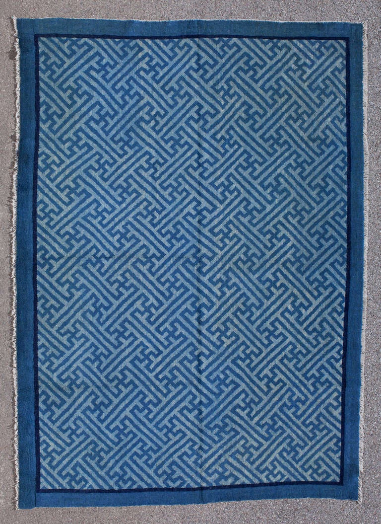 This elegant Peking rug shows an all-over swastika design, one of the oldest symbols used in art in all ancient cultures. The swastika has various meanings including the wish for a long life. A thin indigo blue line and a wider medium blue border