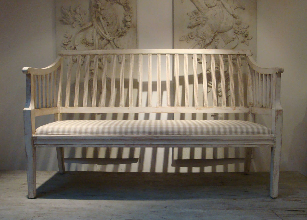 Early 20th century Swedish bench with slatted back and sides, seat covered in beige and white check fabric