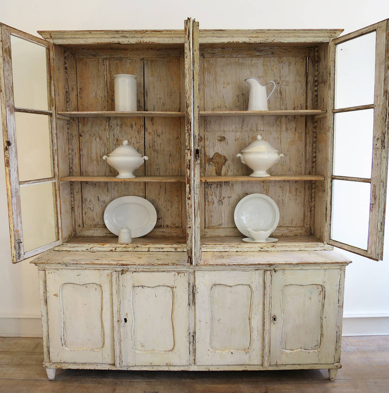 A charming French 18th century painted pine Dresser/ Bookcase.  In very good order and with remains of old  creamy/white paint. 4 panelled doors to base with 4 glazed doors to the top with original old glass. Adjustable shelving. Lots of character