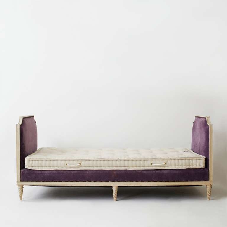 This Louis XVI-style painted daybed by Maison Carlhian is a beautiful example of neoclassical style. It is supported by six tapered legs carved in a torsade. Newly upholstered in purple velvet. Includes a custom traditional mattress innerspring and