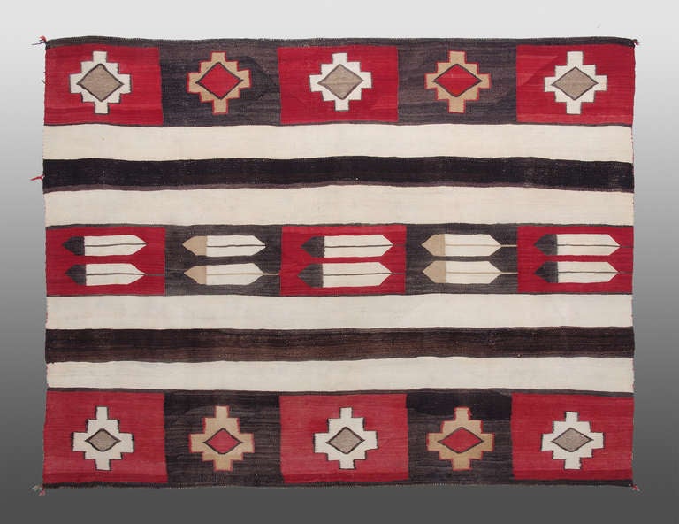 A Navajo Trading Post Era rug.  This is a unique variation on a Chiefs blanket pattern which incorporates pictorial feather motifs against a classic banded ground.  

Well suited for use on the floor or as a wall hanging.