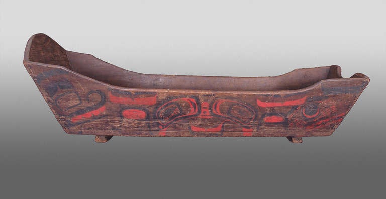 An exquisite Native American Indian child's cradle. Intricately painted in red and black pigment in designs indicative of Northwest Coast tribes and constructed of cedar boards with two rockers.

An accompanying label states that this cradle was