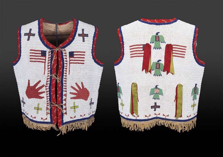 An impressive antique Plains American Indian vest fully beaded on both sides with a number of motifs including American Flags, crosses, thunderbirds and hand prints with trade ribbon suspensions; fringed along the bottom.

Custom Table Stand