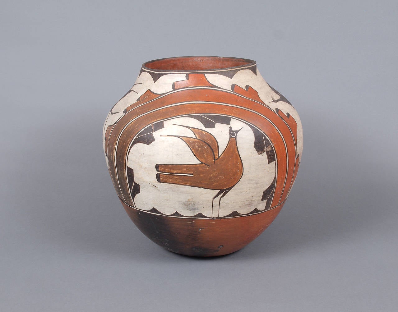 A large earthenware jar created at Zia Pueblo during the first part of the 20th century.  The earthenware vessel was expertly painted in a polychrome design with bird and rainbow motifs.