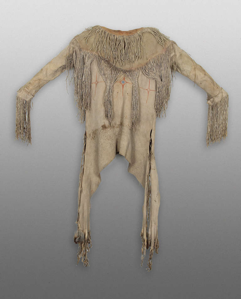 A Man's War Shirt constructed of native tanned hide in a traditional Kiowa design with fringe and painted with geometric elements.  This shirt was owned by Ongotoya (Solitary Traveler) - a Kiowa warrior.  Refer to photograph of him wearing this