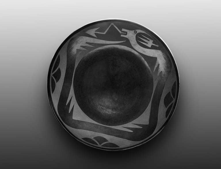 An earthenware plate with an Avanyu (water serpent) motif in Martinez's hallmark black on black gunmetal style, matte against a highly polished black slip. Signed 