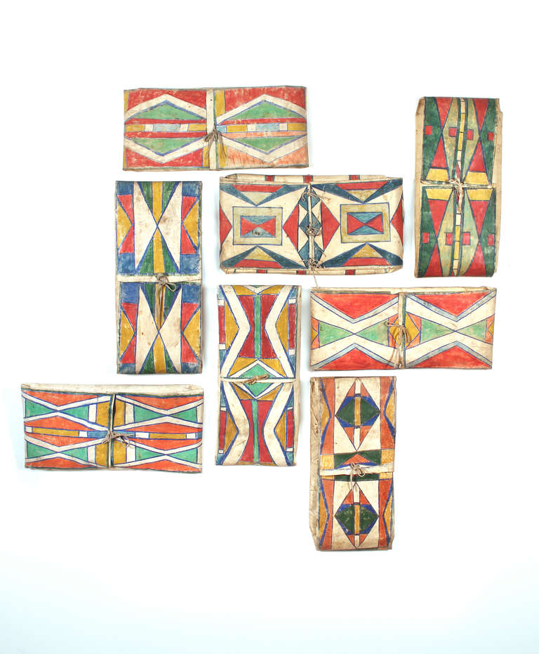 Eight individual Parfleche envelopes have been arranged as a wall installation. Each three dimensional container is constructed of rawhide (buffalo or cow). Painted in unique abstract compositions by members of the Crow and Plateau Peoples between
