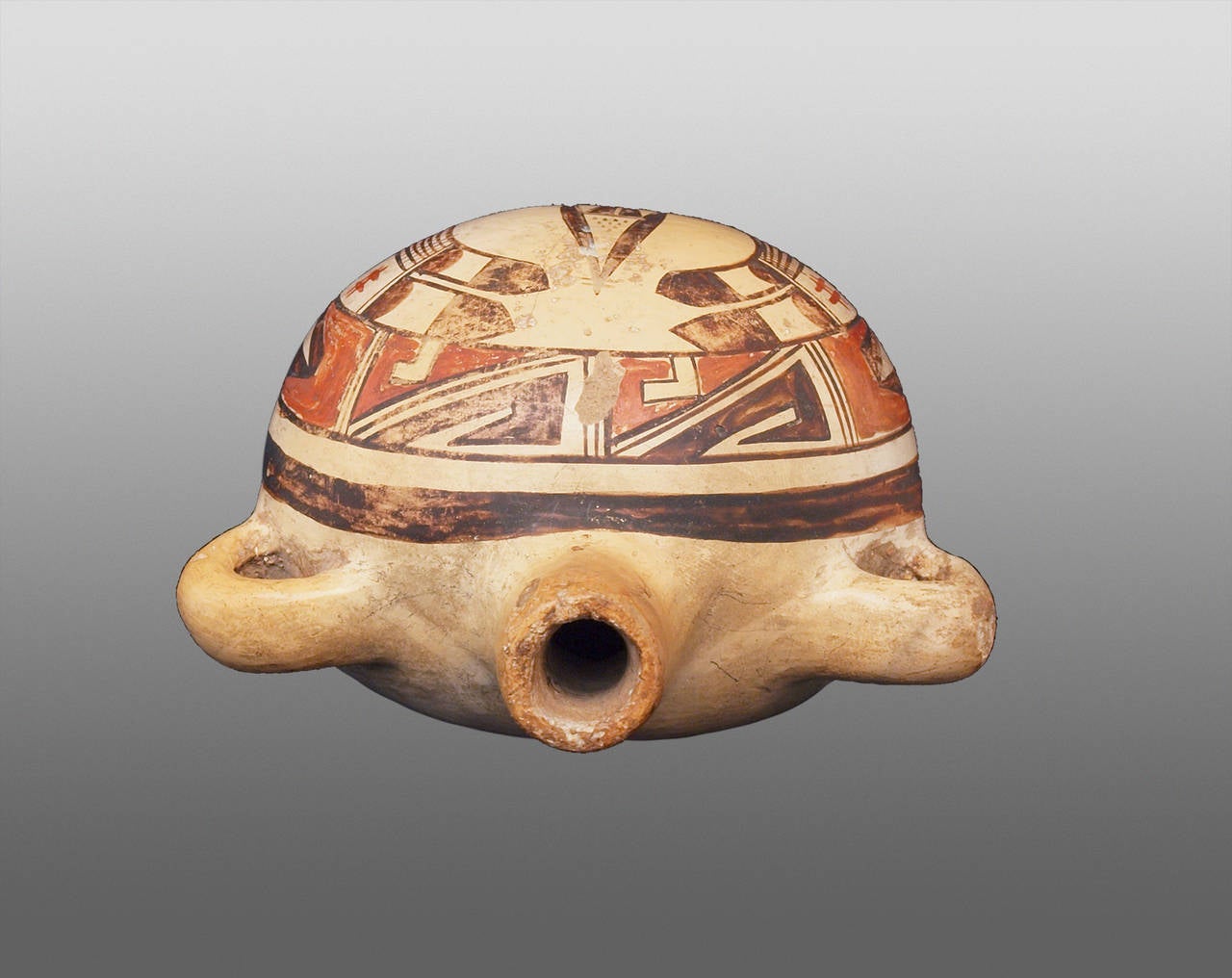 This exemplary earthenware canteen is finely painted in polychrome in a complex Prehistoric Revival pattern. The quality, characteristics and age of this piece are consistent with the work of the renowned Hopi potter, Nampeyo (1860-1942), to whom