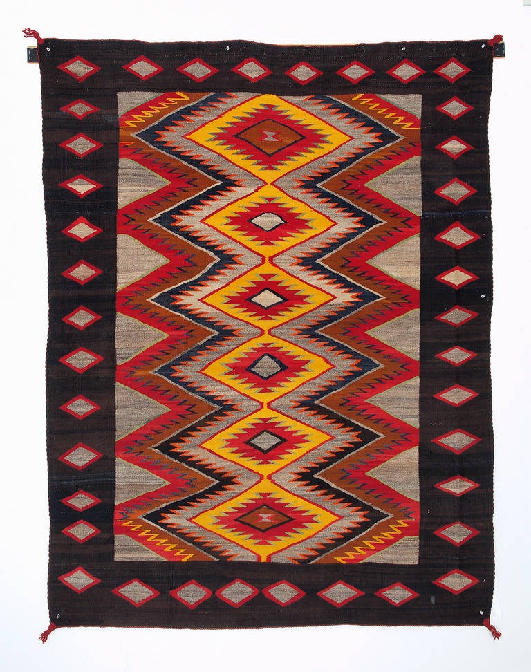 A regional or trading post rug. Woven of native hand-spun wool in natural brown, gray and black fleece with aniline dyed red, yellow, orange, blue and green.

This textile is well suited for use as an area rug, wall hanging or bed covering.