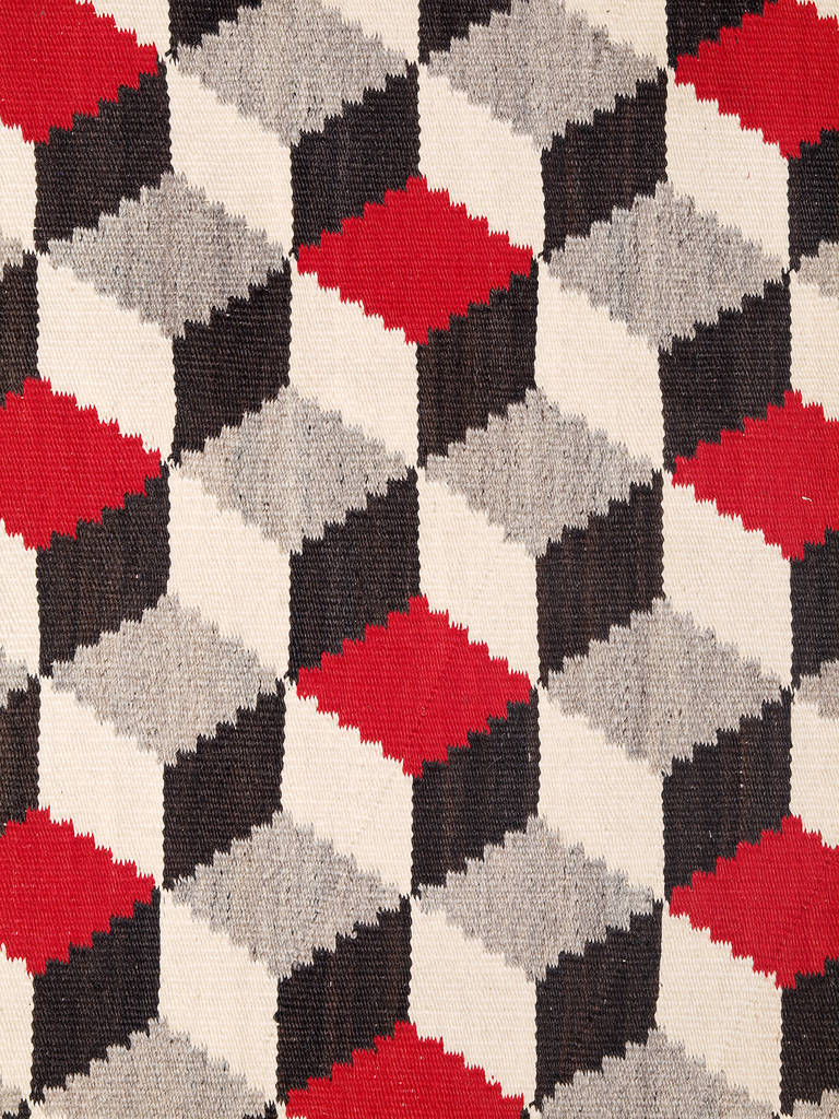 A fine example of an optical or tumbling Block style rug.  Expertly woven by a Navajo weaver of native hand-spun wool in natural gray, white and black fleece with aniline dyed red.

This textile is well suited for use as an area rug or as a wall