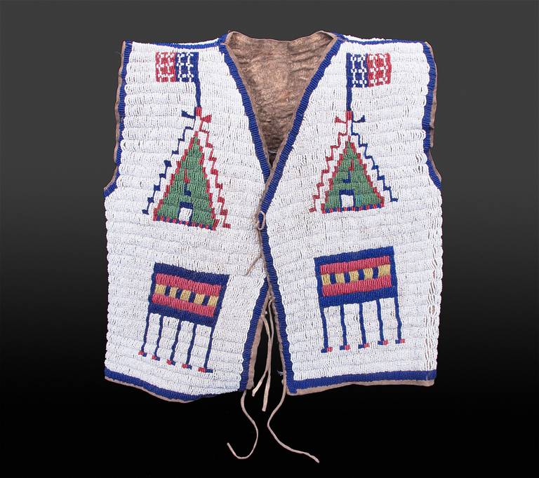 This vest, which was likely made around 1880 by a member of the Sioux tribe, is constructed of native tanned buffalo hide sinew-sewn and beaded.  Pictorial elements include stylized American flags and tepees in green, red white-heart, blue, greasy