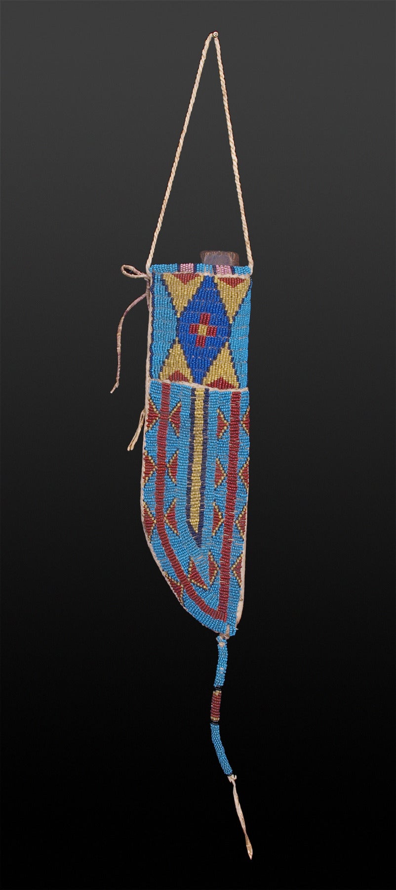 Constructed of native tanned hide, this 19th century Plains Indian knife sheath is expertly beaded in blue, yellow, black and red trade beads with stylized tepee and geometric motif. Suspension is fully beaded in the same colors.  Custom display