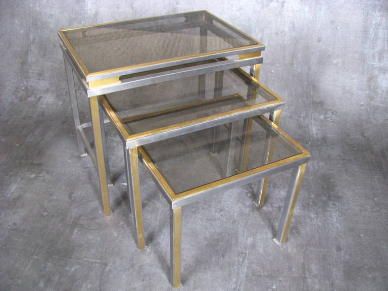 1970s nesting tables by Guy Lefevre for Maison Jansen.

Set of three nesting tables from Lefevre for Maison Jansen, late 1960s-early 1970s. Chrome and brass mounts in good vintage condition. Original smoked glass tops in rosy quartz color. Glass