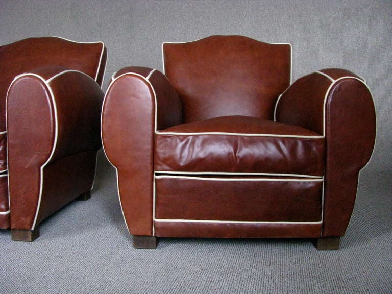 A pair of Art deco clubchairs, france 1935, typical pre-war mustache shape. 

Full restored in traditional manner with coir and spring frame, upholstered in southafrican oil pull up brown buffalo leather with a nice two tone effect and white
