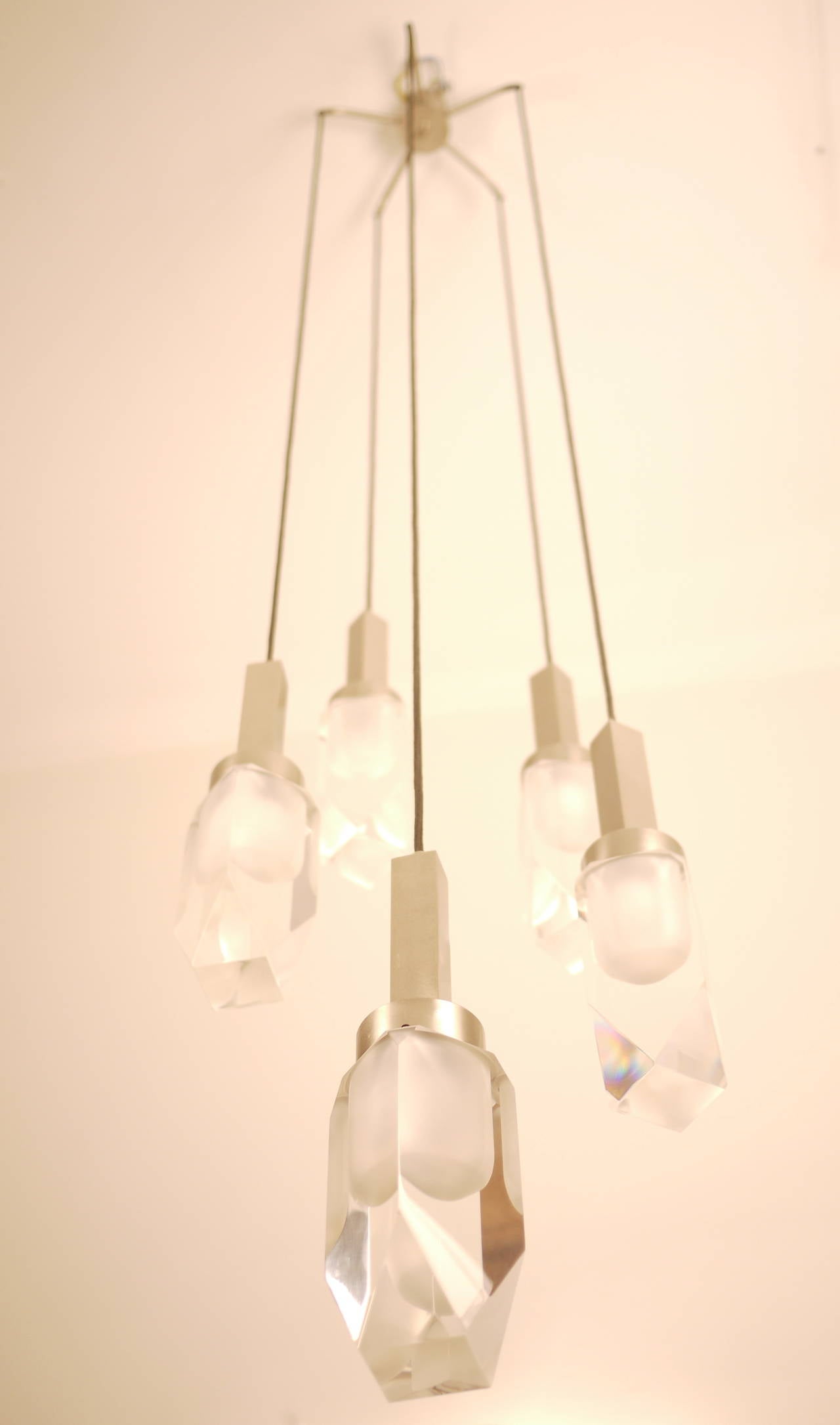 A very elegant and exclusive 1960s Stilnovo five-pendant hanging lamp. Five diffusers in opaque nickel-plated brass and plexiglass. Mark imprinted on the metal.