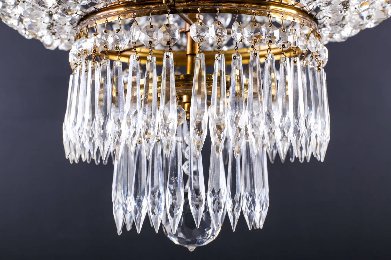 Chandelier in the Regency Style English Circa 1920’s

A large cut glass and gilt bronze four light Chandelier in the Regency style, with beaded ropes descending from the top to the waterfall of hung spear drops and a large cut glass globe, English