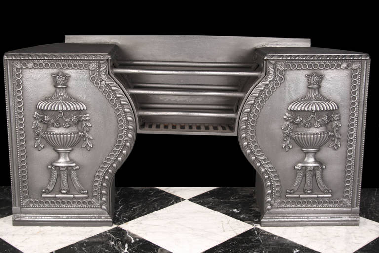 A very large Georgian hob grate in the Roman Revival manner of Robert Adam, with large urns and bellflower decoration on the side panels, English, early 19th century.

External height: 22” - 55.8 cm.
External width: 42