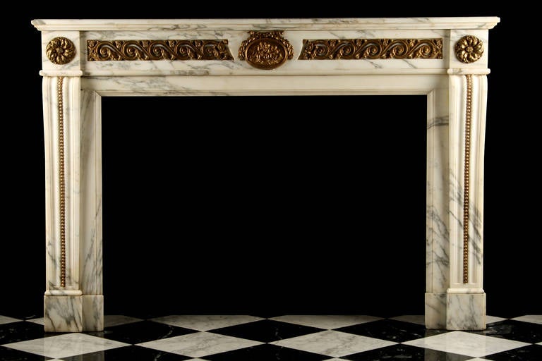 An Impressive Louis XVI fireplace mantel in the French Regency manner, in nicely veined white pavonazzo marble, decorated with very fine quality gilt bronze vitruvian scrolls, representing the waves, on both sides of a charming gilt bronze central