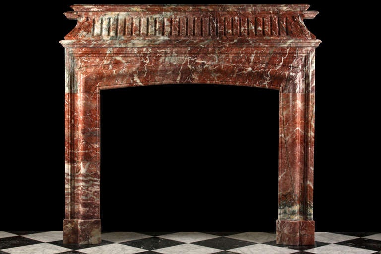 A remarkably tall Antique Louis XIV 'Bolection de Versailles' Chimneypiece carved in richly figured and veined Sarin Colin marble, with a concave fluted frieze and large floral end decoration on top of a surround with bold bolection moulding, French