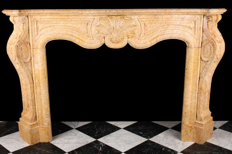 A finely carved Louis XV antique fireplace in Crema Valencia Red Veined Yellow marble, decorated with large central scrolled shell cartouche and scrolled fluted jambs beneath a serpentine shelf, French 19th century circa 1830.

Depth: 15