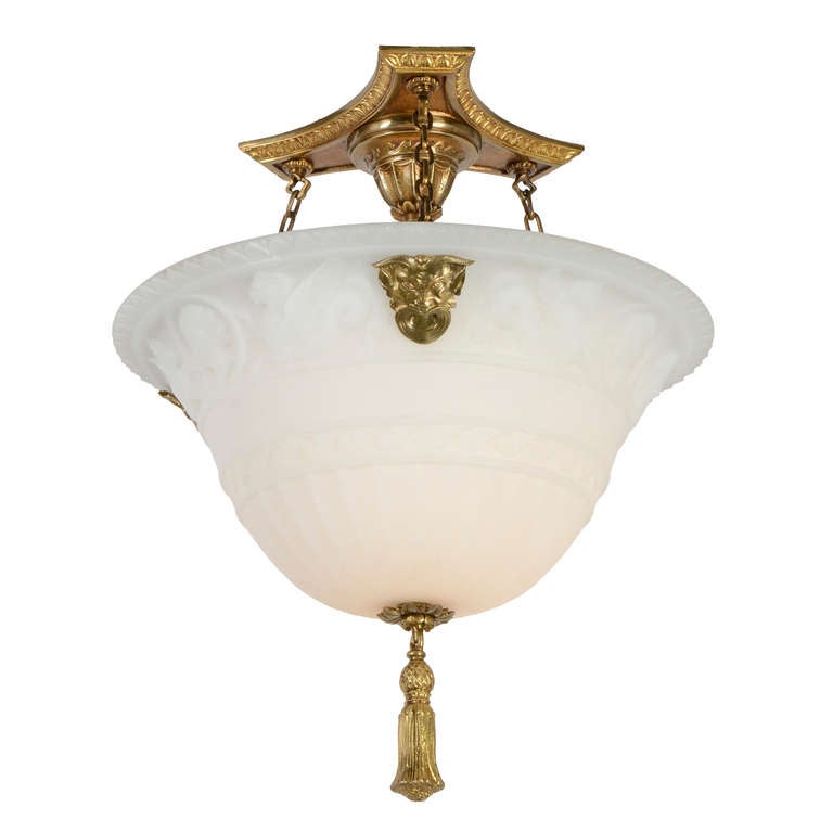 Bold and substantial, yet subtle and elegantly restrained, this bowl chandelier has a lovely decorative canopy assembly from which 3 delicate chains extend to support the fantastic cast glass bowl via grimacing brass bacchanalian faces. This bowl