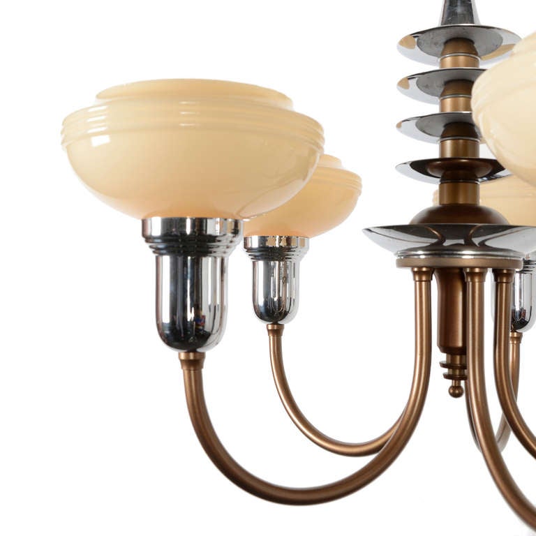 The refined aerodynamic appeal of the clean lines and sleek contours of this stunning cup shade fixture epitomize machine-age elegance.  The chrome accents are in lovely contrast to the bronze-tone paint, and the creamy custard glass cup shades