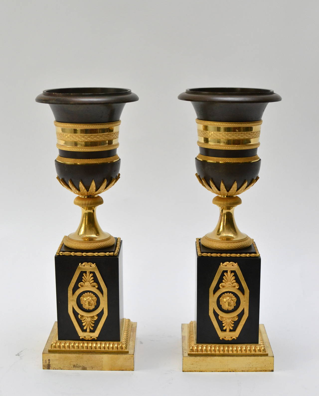 A unusual pair of gilt and patinated bronze Empire urn shaped candlesticks, France, early 19th century.