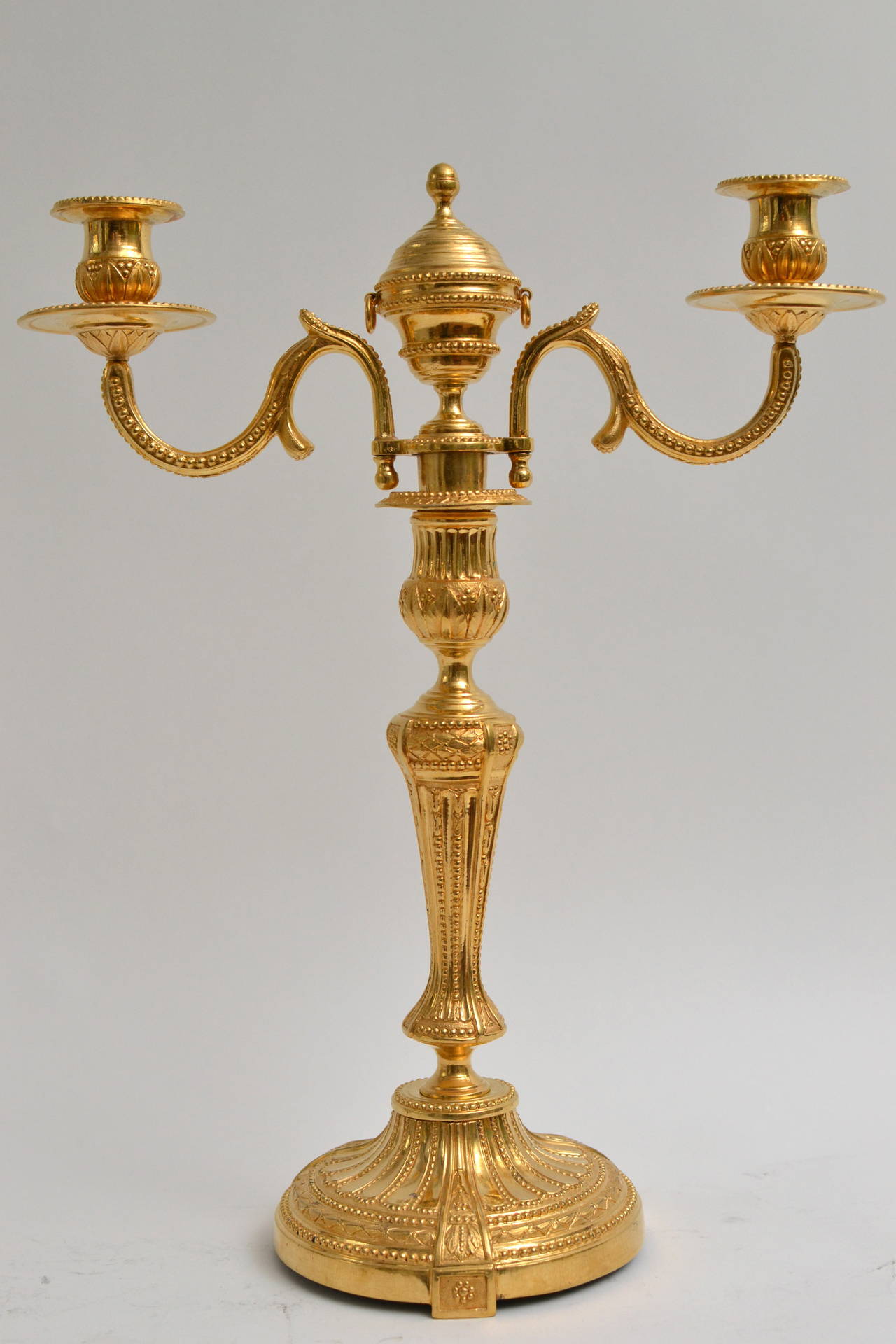 A pair of gilt bronze Louis XVI candelabra, circa 1780. A very decorative pair of three-light candelabra with detachable top. The centre made as an cassolettes. Regilt.