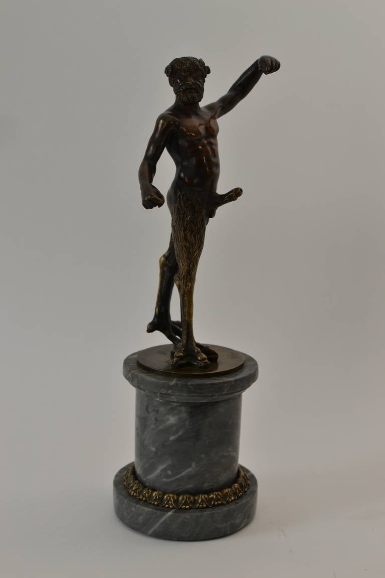 A 18th century bronze figure of a satyr on a marble base.