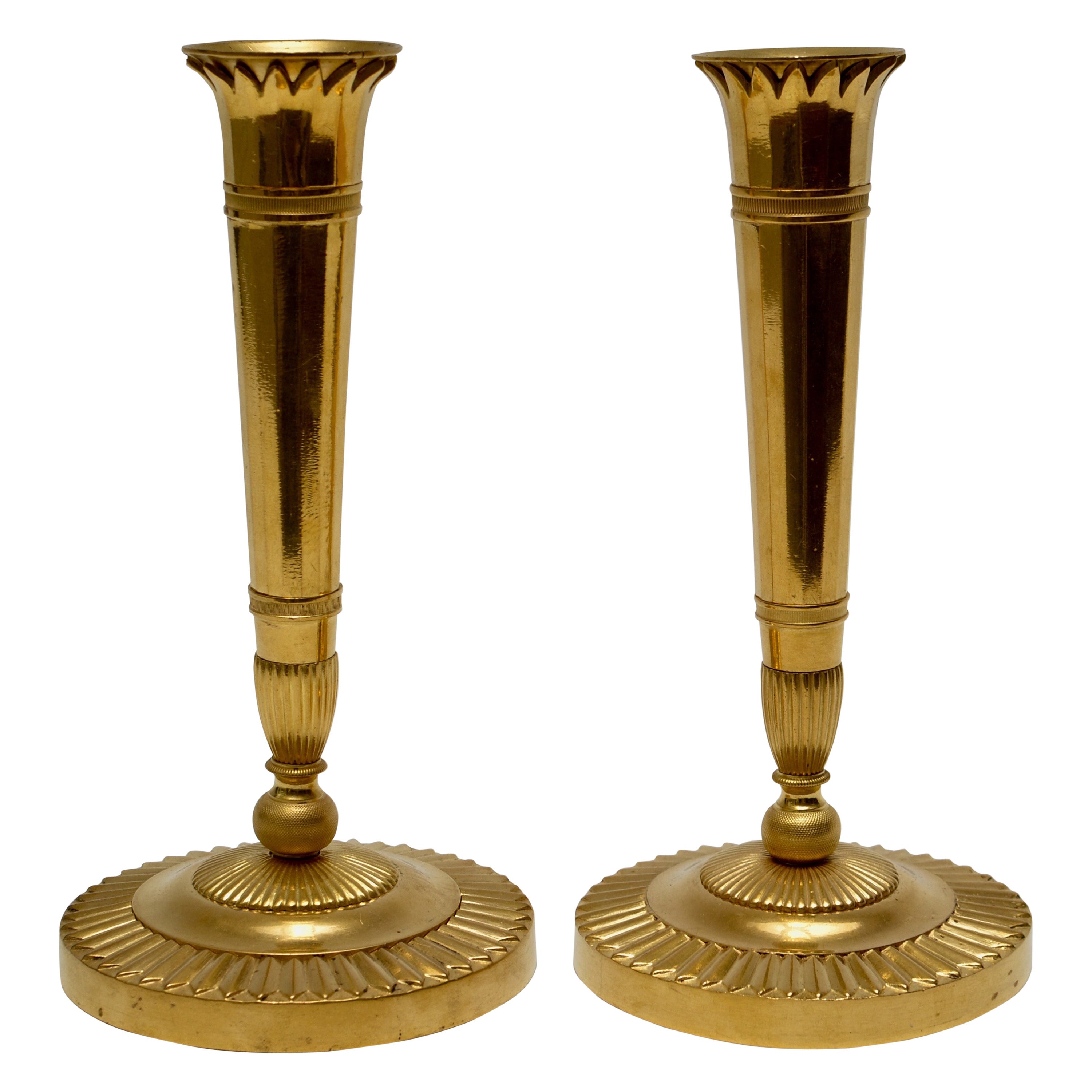 A pair of French empire gilt bronze candlesticks, early 19th century.