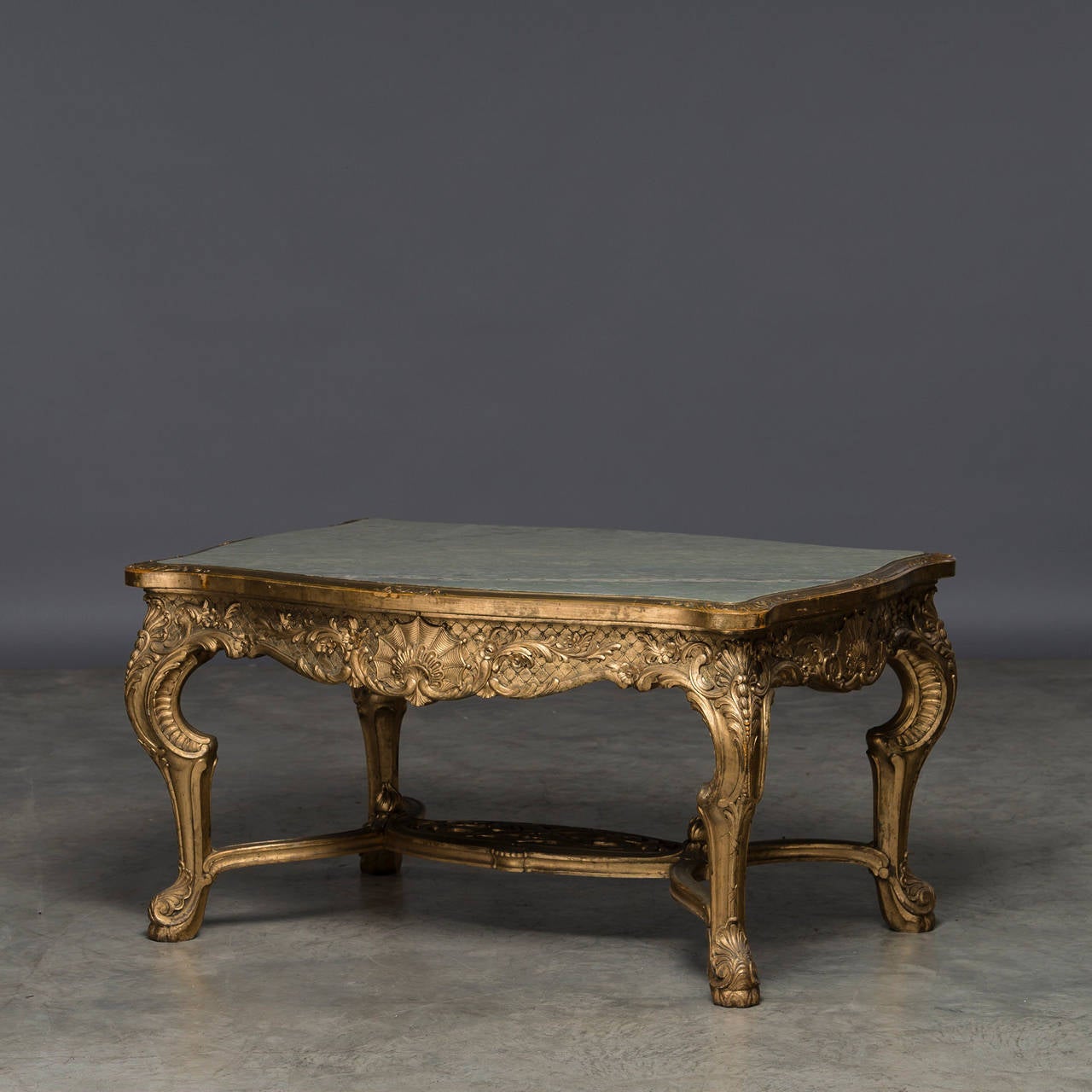 Salon table from Fredensborg Palace - Royal furniture marked with Frederik VIII and Louisas crowned monogram and F90 (for Fredensborg). Wood carved and gilded with a stretcher base. Richly carved with mussel, rocailles, flowers and foliage. The