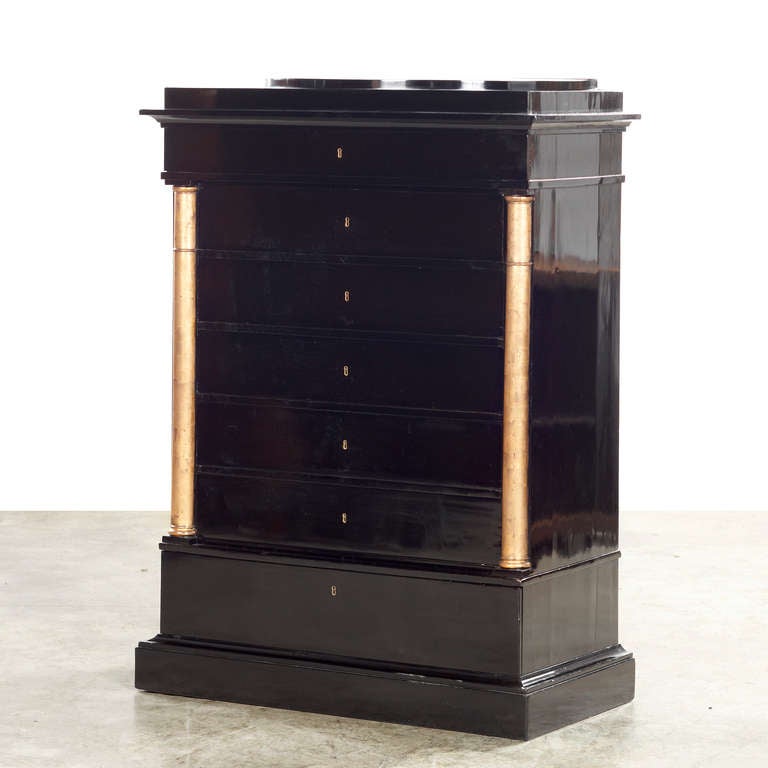Late Empire black ebonized mahogany chest of drawers / tall boy, with raised semi-oval top.
Seven drawers flanked by gilt quarter columns.
Brass keyholes.

Denmark, Copenhagen  Approx. 1830-1840.