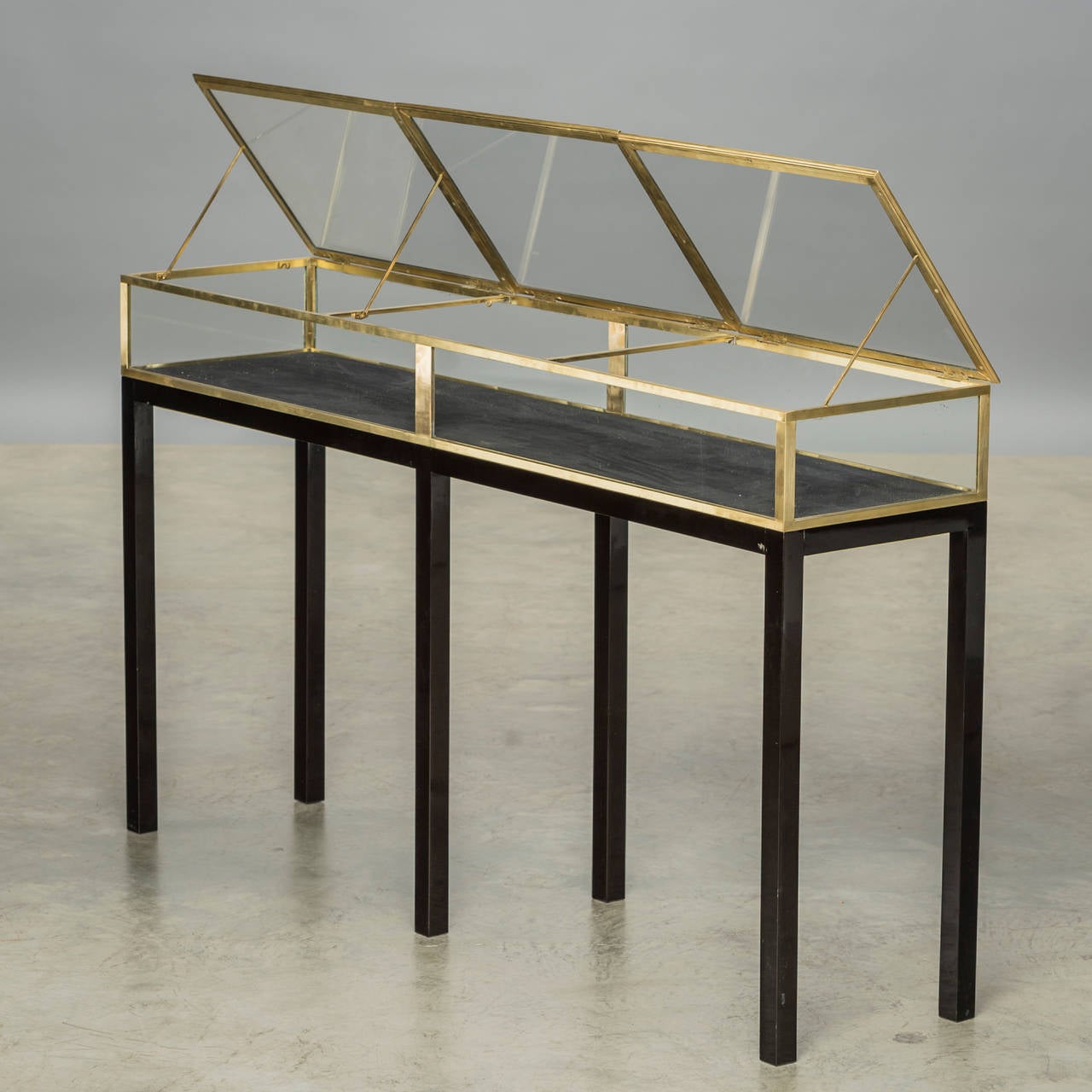 Beautiful Art Deco display case in brass and glass, elegantly made and in good quality. Three liftable doors, black polished wooden frame (later). Bottom inside covered with black velvet,
France, 1920-1930.