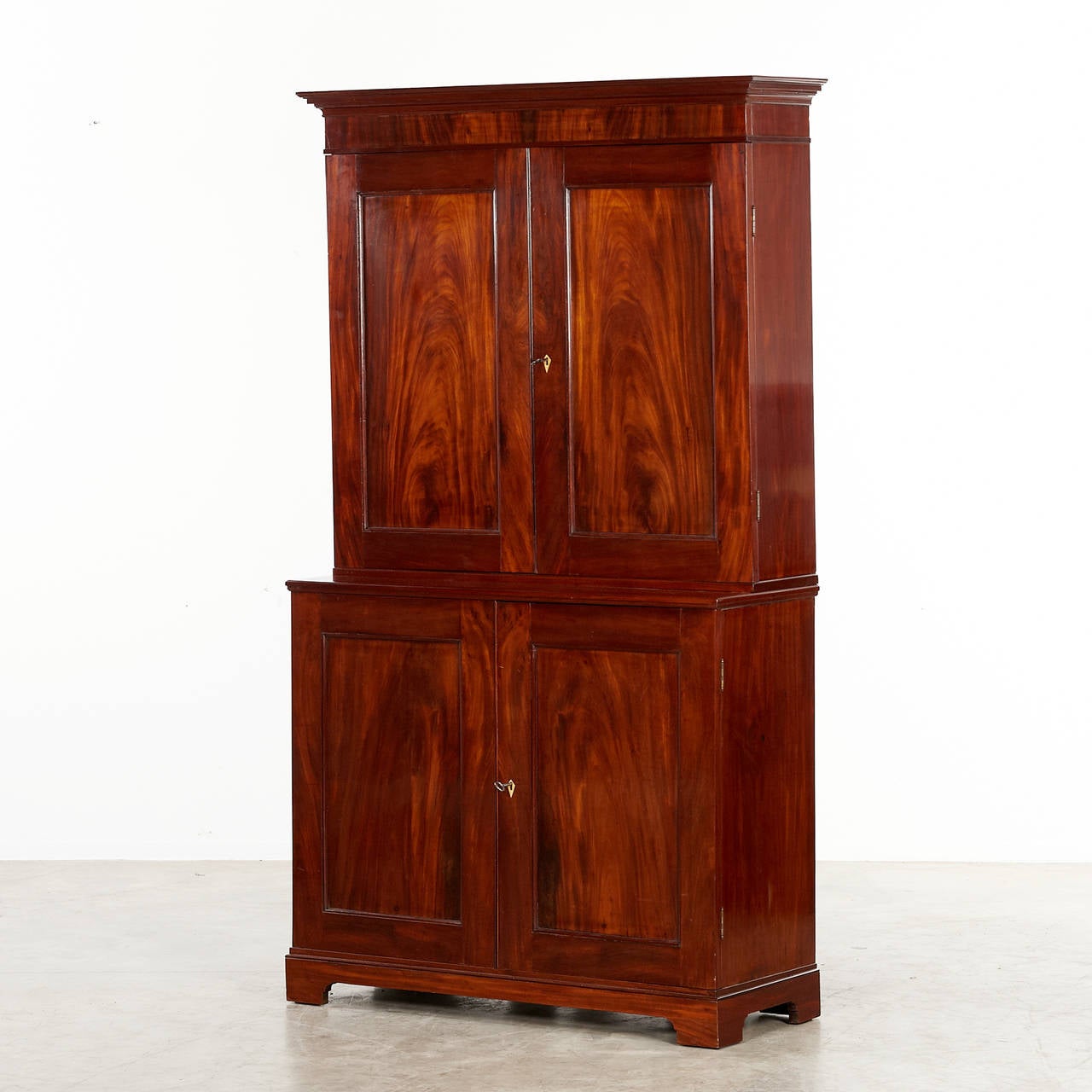 Elegant empire cabinet separated in two parts with each two doors and inside with adjustable shelves. Veneered with flamed Cuban mahogany. Denmark, circa 1810.