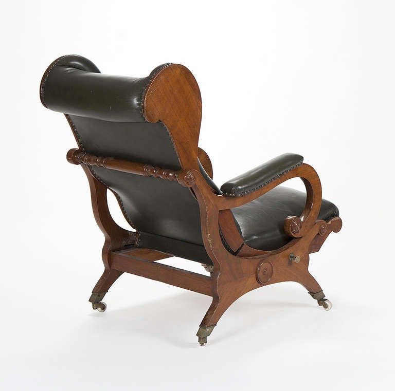 A veneered Biedermeier armchair.The feet are terminated with brass and copper and then porcelain roller wheels  Upholstered with green  dyed leather. Seat and backrest in adjustable mahogany. The Biedermeier period refers to an era in Central Europe