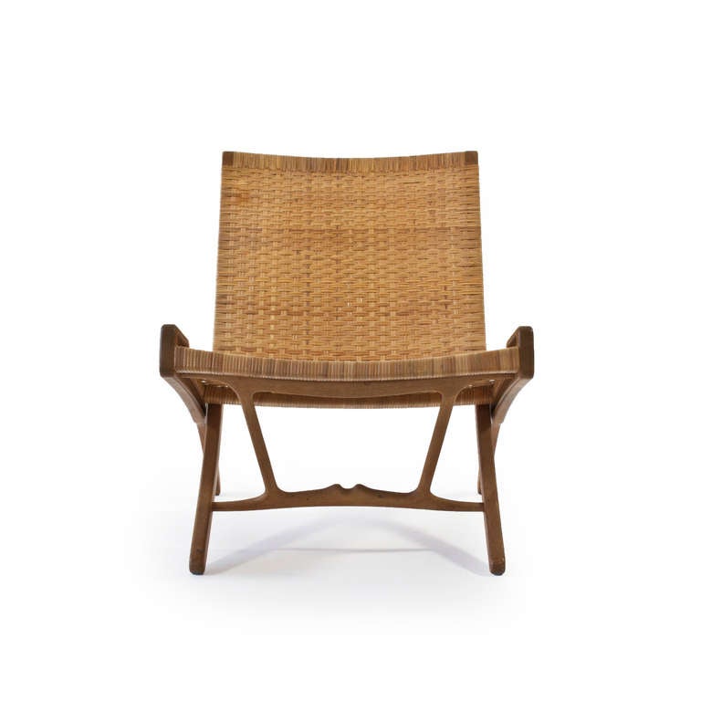 The Hans J. Wegner folding chair.

Frame of patinated oak, seat and back of original woven cane. 

Designed 1949, manufactured and burn marked by master cabinetmaker Johannes Hansen, Denmark, model JH-512.