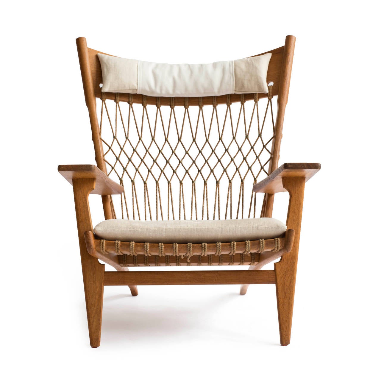 A rare Hans J. Wegner oak armchair model JH-719. 

Designed 1968 and made by cabinetmaker Johannes Hansen. 

Frame of oak, seat and back with woven flag line and brass details. Seat and head cushions upholstered with light fabric. 

Very fine