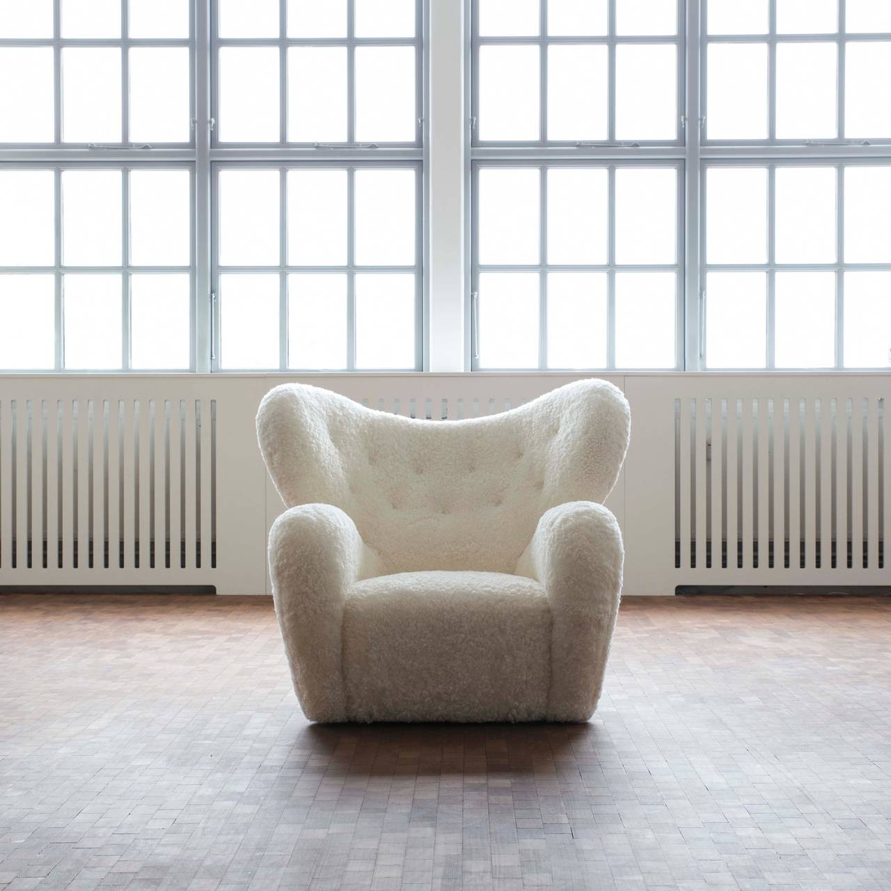 Rare Flemming Lassen 'The Tired Man.'

Upholstered with white sheepskin, partly fitted with buttons. Hind legs of elmwood, front legs made of brass and bakelite wheels. 

Designed by Flemming Lassen 1935 /1936 and made by cabinetmaker A. J.