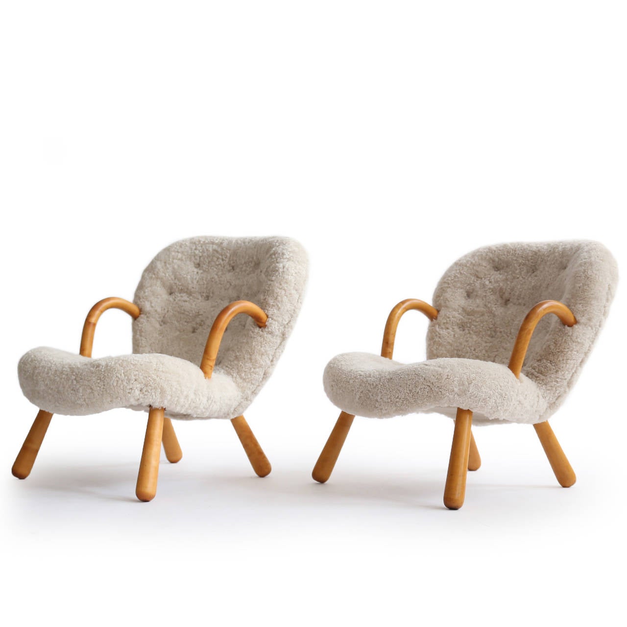 A pair of Philip Arctander clam chairs with legs of birch, upholstered with lamb skin fitted with buttons. 

Designed by Philip Arctander, Denmark 1944 and manufactured by Nordisk Stål & Møbel Central, Denmark.
