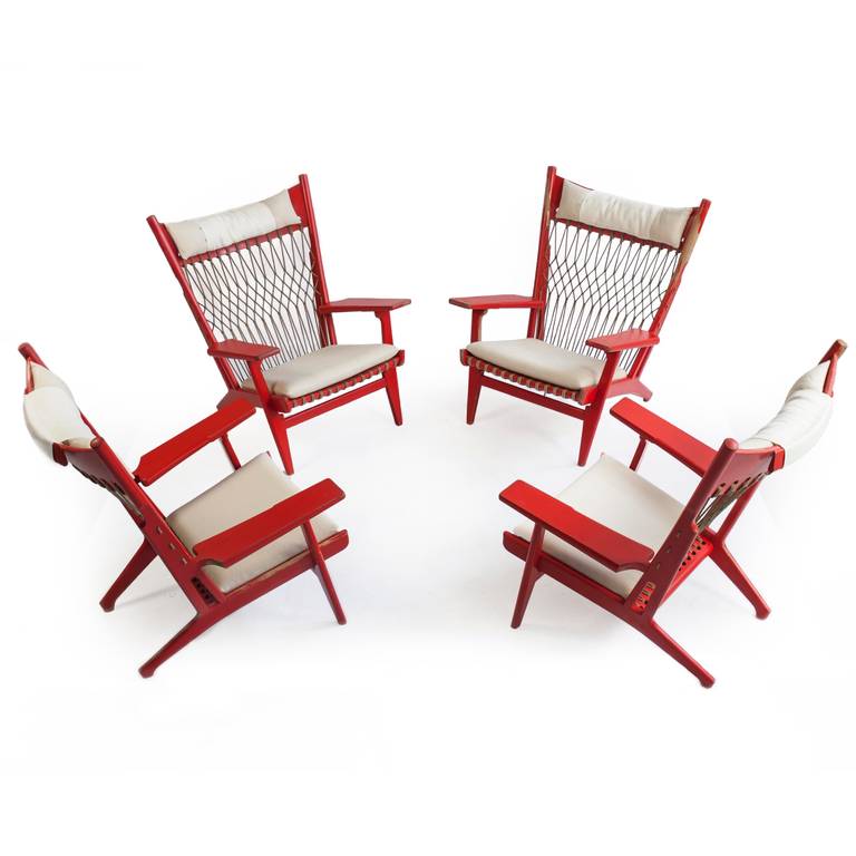 A very rare set of four Hans J. Wegner armchairs. 

Designed 1968 and made by cabinetmaker Johannes Hansen, model JH-719.  

Frame of red lacquered beech, seat and back with woven flag line and brass details. Seat and head cushions upholstered