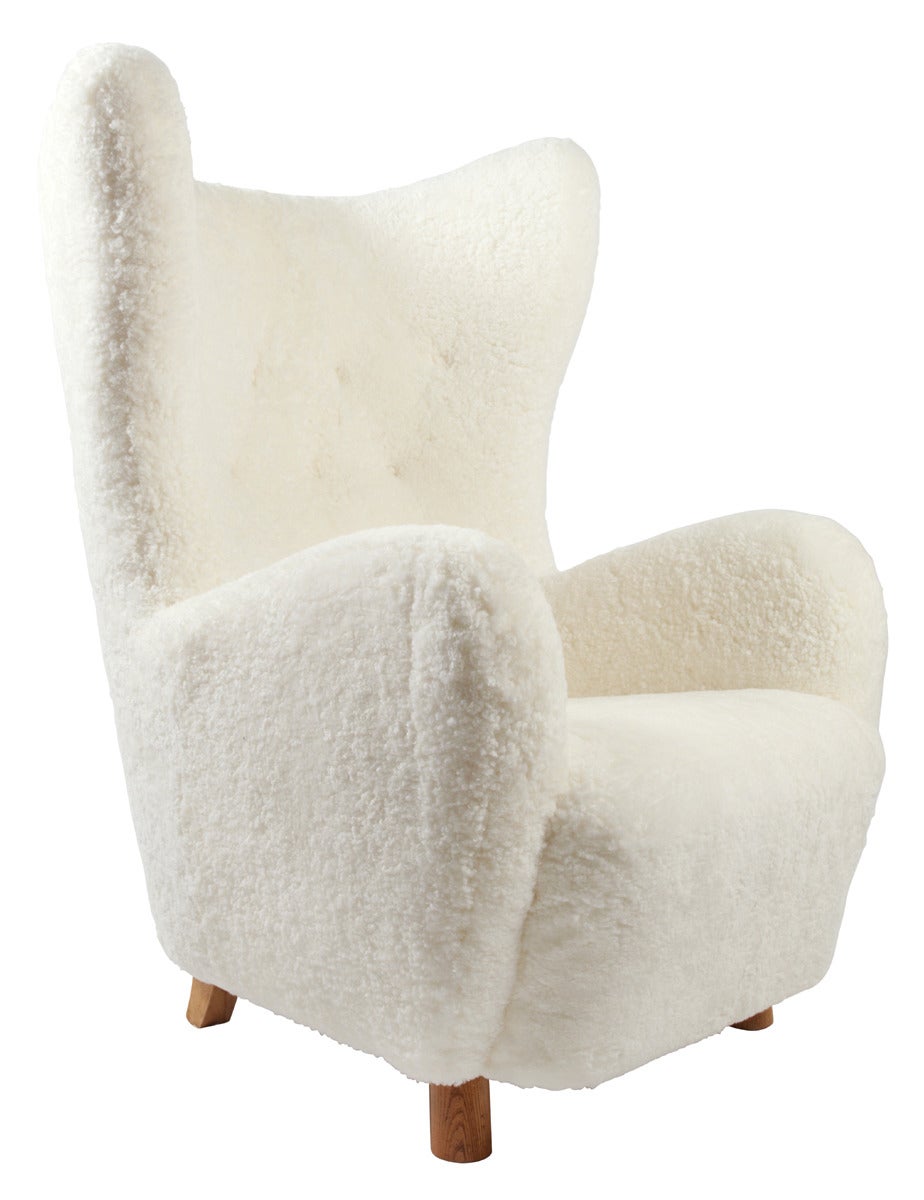 Freestanding highback chair mounted on round oak legs. Sides, seat and back upholstered with white sheepskin, back fitted with buttons. Designed 1930´s