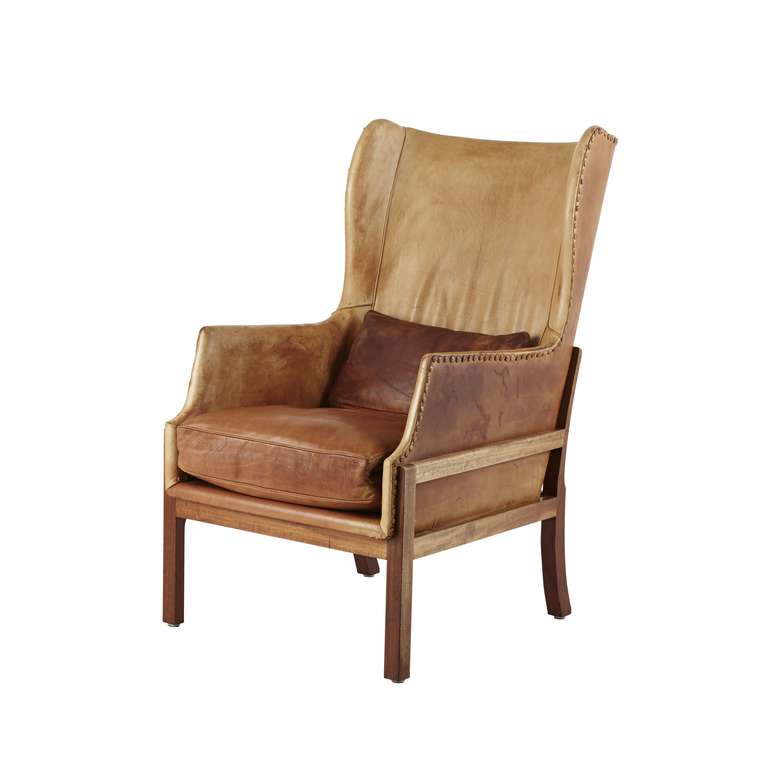 Mahogany wingback chair with matching stool. Sides, back and loose cushions upholstered with patinated natural leather, fitted with leather covered nails. Model MK-50. Designed 1936. Made by Ivan Schlechter