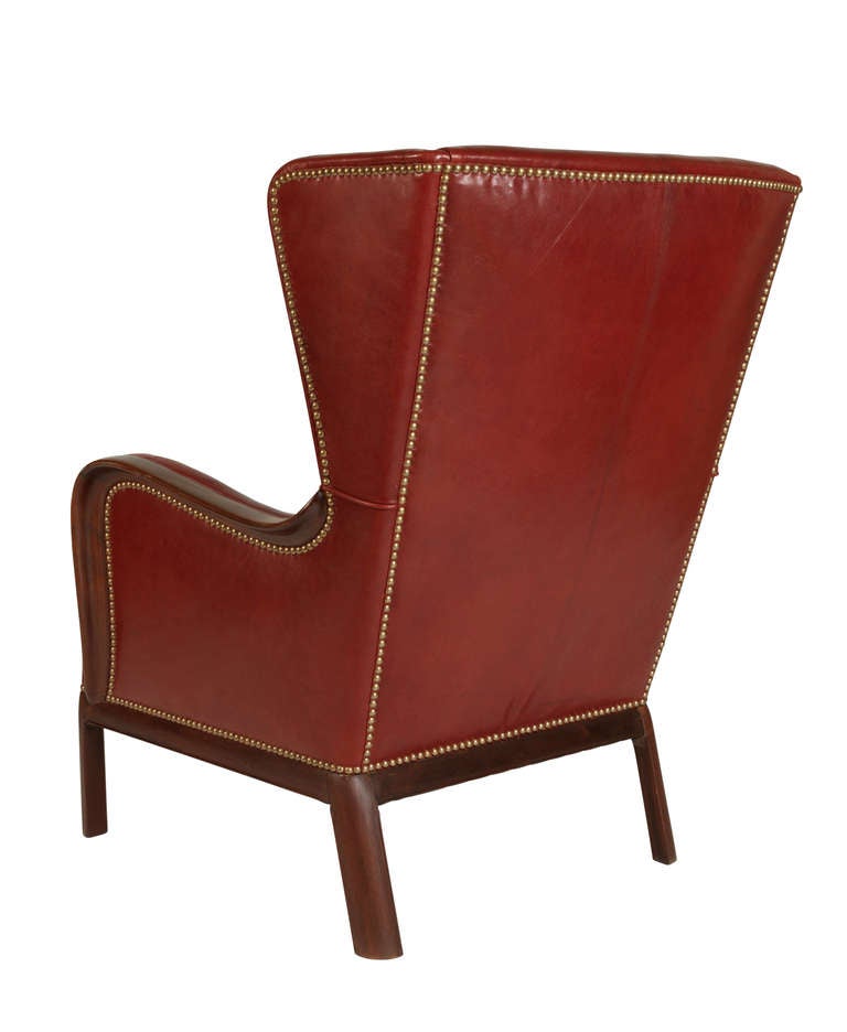 Highback wing chair with Cuban mahogany frame. Seat and back reupholstered in partially studded Niger goat leather.
Produced by master cabinetmaker Frits Henningsen