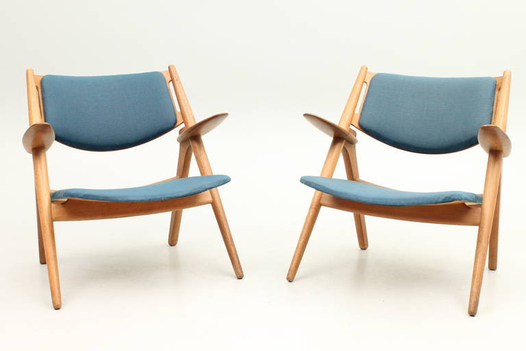 Pair of CH28 Sawback loungers in oak with original fabric. Designed in 1951 by Hans Jørgen Wegner and manufactured by Carl Hansen and son, Denmark.